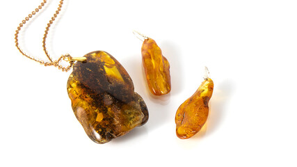 Luxurious old green and yellow rare Baltic amber pendant with gold chain  and long sparkling amber earrings on a white background. Ancient amber with plant inclusion.