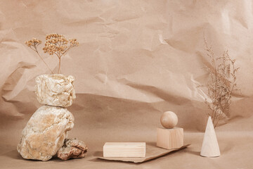 Creative podium for cosmetics or you merchandise, products. Layout made of from wooden geometric shapes, stones and dried flowers on beige paper background Front view