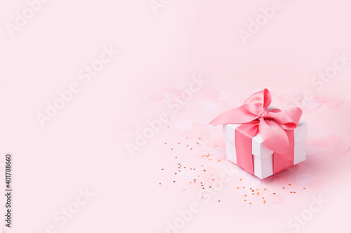 Holiday pink background with gift, white satin bow, ribbon. Valentine's Day, Happy Women's Day, Mother's Day, Birthday, Wedding, Christmas. space for text, banner, flyer