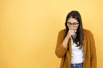 Young beautiful woman wearing a blazer over isolated yellow background coughing with the hand next to the mouth