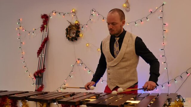 Christmas season music: Xylophone player hands with sticks making wooden sounds. hands of a musician playing the marimba. attractive handsome caucasian musician playing Xmas carols songs