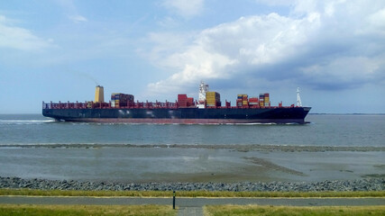 Fototapeta premium a big cargo ship is navigating along mudflats in the westerschelde sea in summer 