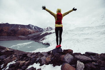 Successful woman trail runner open arms to winter fossil glacier snow mountains