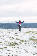 vertical photograph of an unrecognizable mountaineer with his arms raised, taking a break and contemplating the beautiful winter landscape of a snowy mountain range. hiking in winter.