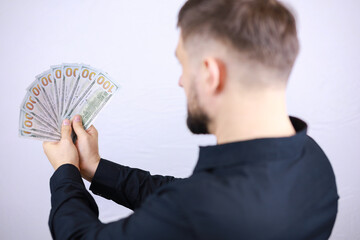 a man businessman stands with his back and holds bills in his hands