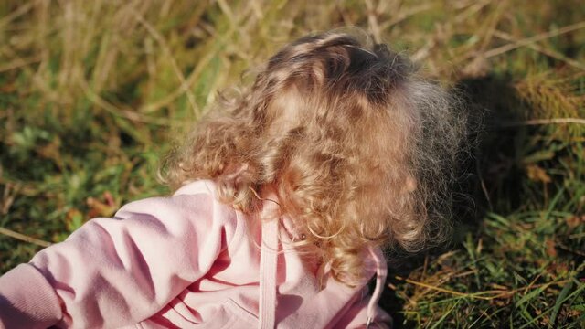 Child lying in the grass enjoying the summer. Baby with blond curly hair.