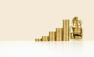 Stacks of increasing coins and glass bottle with their reflections on bright background