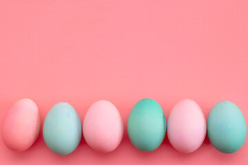 Fototapeta na wymiar Easter decor in pastel colors: turquoise and pink eggs on a pink background, copy space. The photo
