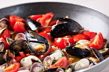 Vongole Seafood Clams with tomatoes and parsley in frying cooking pan.
