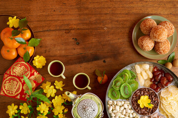 Obraz na płótnie Canvas Plate with fried rice balls, nuts and dried fruits on wooden table with tea cups and greeting cards for Chinese New Year celebration