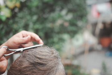 Naklejka premium Cutting an Asian elderly old man with a hair cutting scissors.