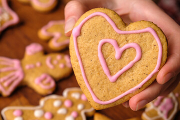 Cookies for Valentines Day in woman hands in the background of gingerbread. 