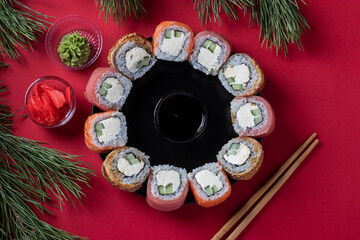 Holiday Christmas brunch sushi set of salmon, tuna and eel with philadelphia cheese as a wreath on a red background. Top view