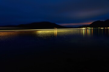 Long exposure of a ferry with strips of light that drives over the fjord at night