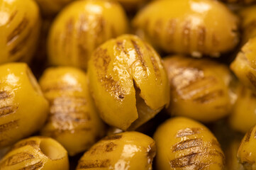 Green marinated olives, pitted, roasted on the grill. The texture of the surface. Close-up, selective focus.