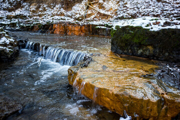 Small waterfalls on the river, limestone layers painted in orange with iron ochre