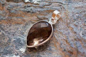 Sterling silver pendant with mineral faceted smokey quartz gemstone on rocky background