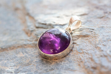 Sterling silver pendant with mineral amethyst gemstone on rocky background