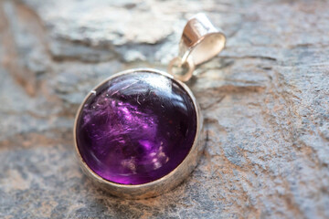 Sterling silver pendant with mineral amethyst gemstone on rocky background