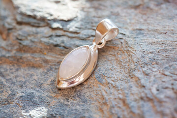 Sterling silver pendant with mineral moon stone gemstone on rocky background