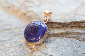 Sterling silver pendant with mineral lapis lazuli gemstone on rocky background