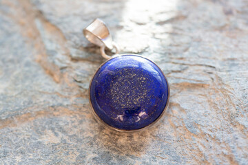 Sterling silver pendant with mineral lapis lazuli gemstone on rocky background