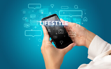 Female hand typing on smartphone with LIFESTYLE inscription, social media concept