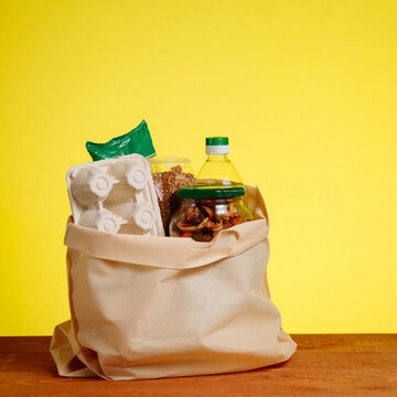 Different Food In Paper Bag on Wooden Table, on Yellow. Grocery Shopping Concept. square image