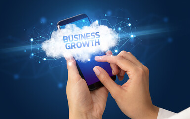 Female hand touching smartphone with BUSINESS GROWTH inscription, cloud business concept