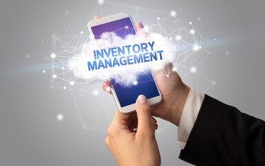 Female hand touching smartphone with INVENTORY MANAGEMENT inscription, cloud business concept