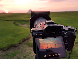 Camera on a tripid ready to take a photo of the Mont Saint Michel at sunset