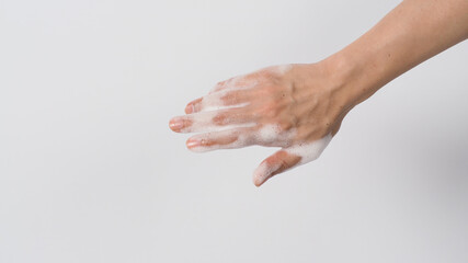 Hand wash gesture with foaming hand soap on white background.