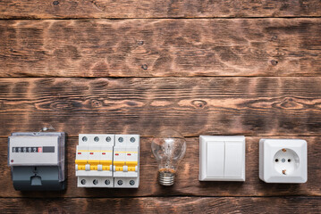 Electric meter, switch breaker, light bulb and outlet on the brown wooden wall background with copy...