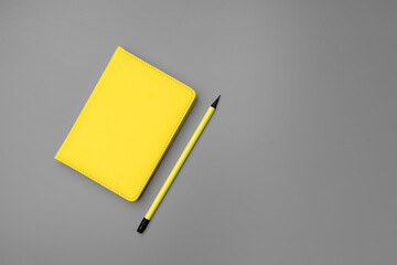 Yellow notepad with yellow pencil on gray background