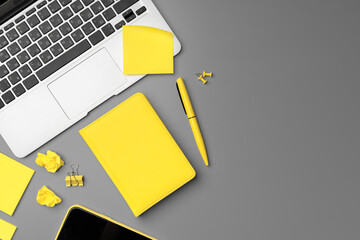 Yellow notepad with smartphone and pen on gray background