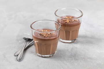 Italian Panna cotta creamy hazelnut cocoa with chocolate sauce and granola in a glass on a light gray background