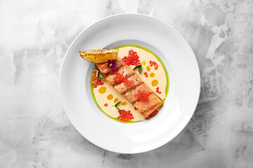Delicious grilled salmon steak filet with creamy sauce in a white plate on a light background. Tasty seafood