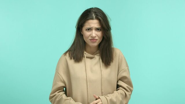 Young caucasian woman feeling embarrassed, covering eyes and grimacing, feeling uncomfortable to look at something cringe and awkward, standing over mint background