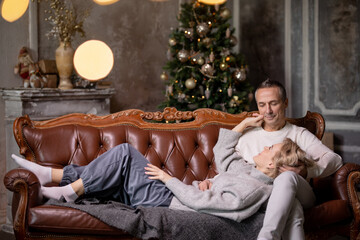 Obraz premium adult woman and man lie on brown couch and hug