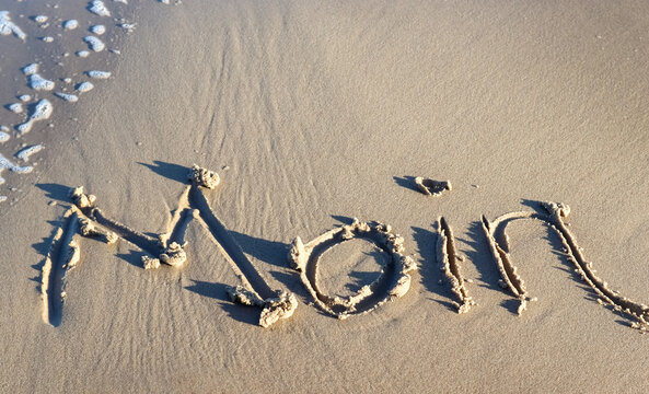 The northern german word Moin (Hello) wrtten into the sand of the baltic sea beach.