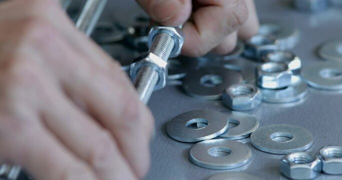 Furniture assembling worker prepares threaded rod and nuts making industrial style design shelves, close up on hand screwing nut, real people