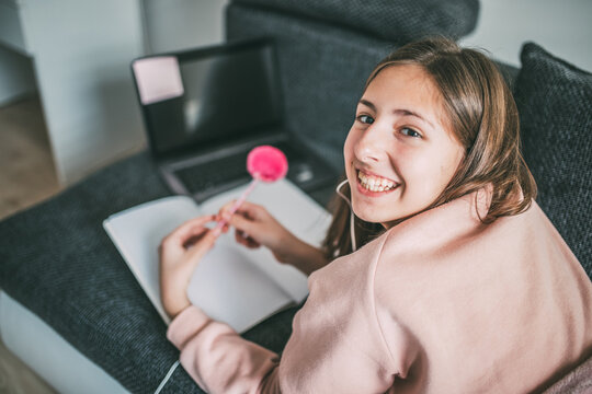 Teenage girl with headphones having online school class at home.
