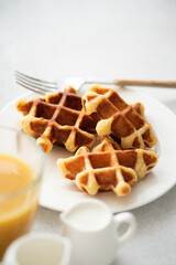 Belgian waffles on white plate. Sweet breakfast golden baked waffles