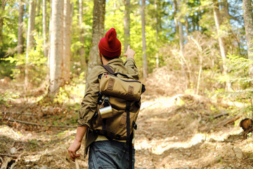 A man traveler walks through the woods. Beautiful wild nature landscape in forest. Hiking journey on tourist trail. Outdoor adventure. Travel and exploration. Healthy lifestyle, leisure activities