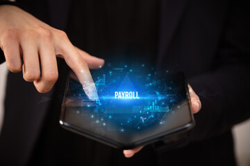 Naklejka premium Businessman holding a foldable smartphone with PAYROLL inscription, business concept
