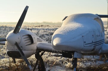 A small plane standing at the airfield, against a blue sky covered with ice

