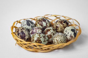 Quail eggs on a white background. Healthy eating. Quail eggs lie in a wicker basket