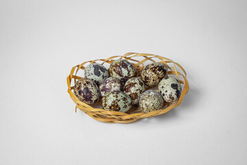 Quail eggs on a white background. Healthy eating. Quail eggs lie in a wicker basket