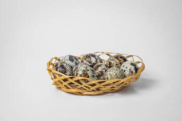 Quail eggs on a white background. Healthy eating. Quail eggs lie in a wicker basket