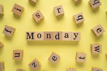 Text MONDAY on wooden cubes with yellow background